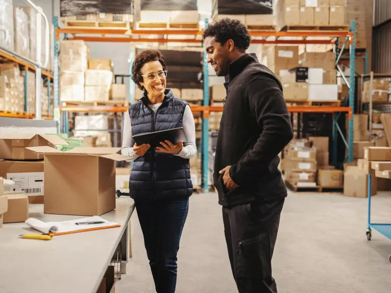 A man and a woman talking in a large shop environment.