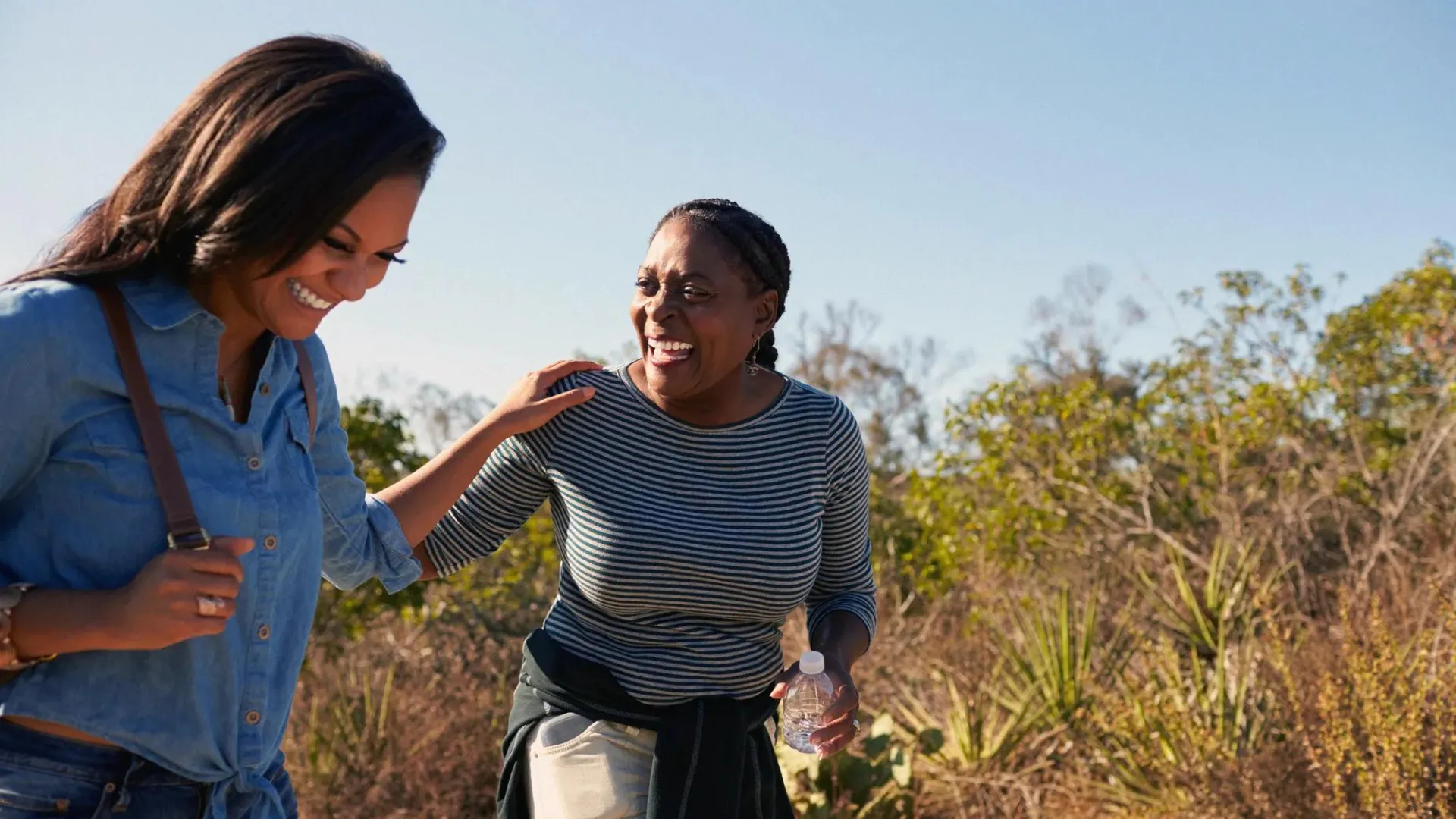 Mother and adult daughter hiking outdoors in countryside.