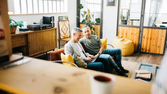 Two men looking at a laptop in a relaxed environment.